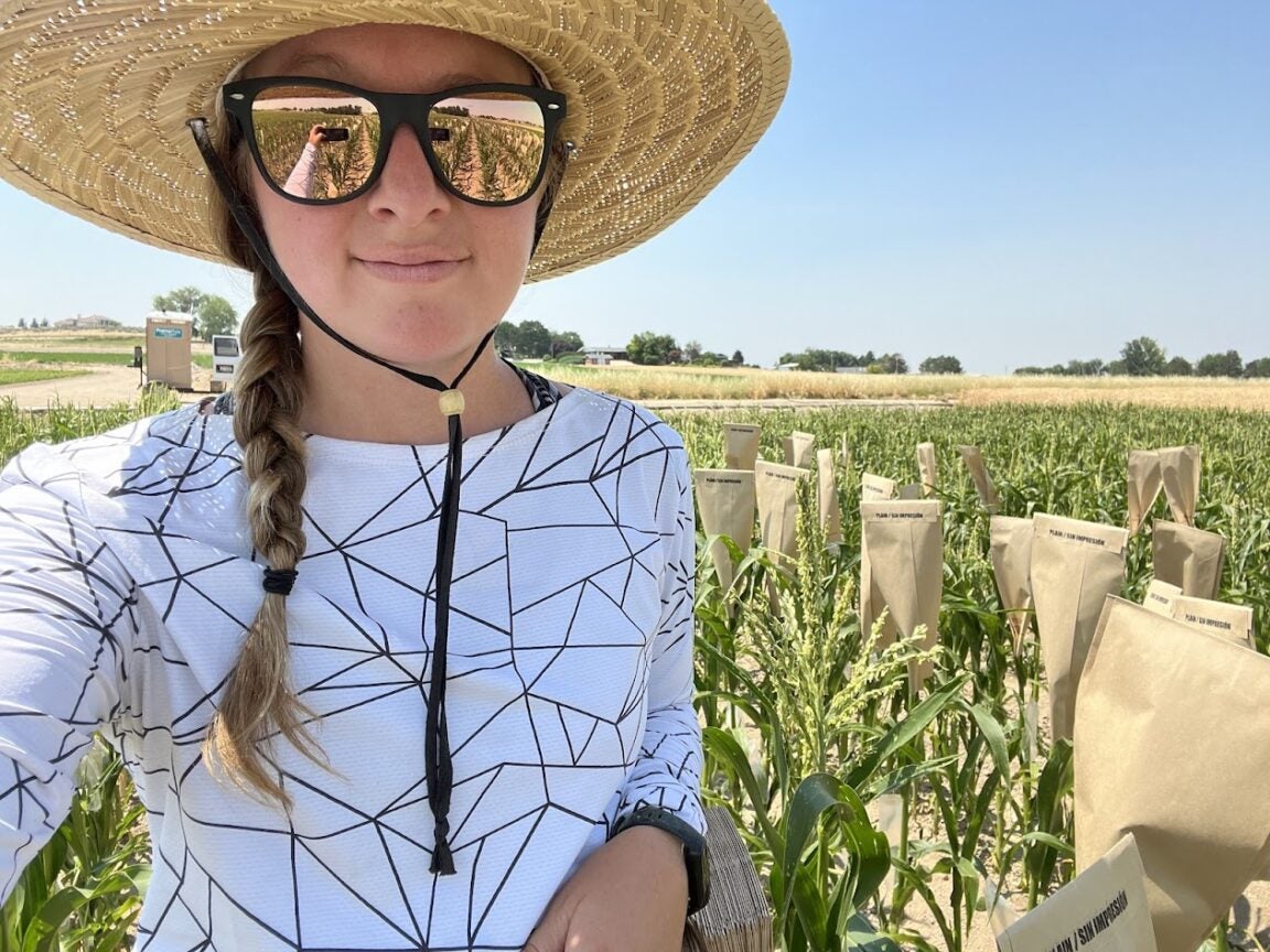 A woman in a straw hat and sunglasses standing in a field