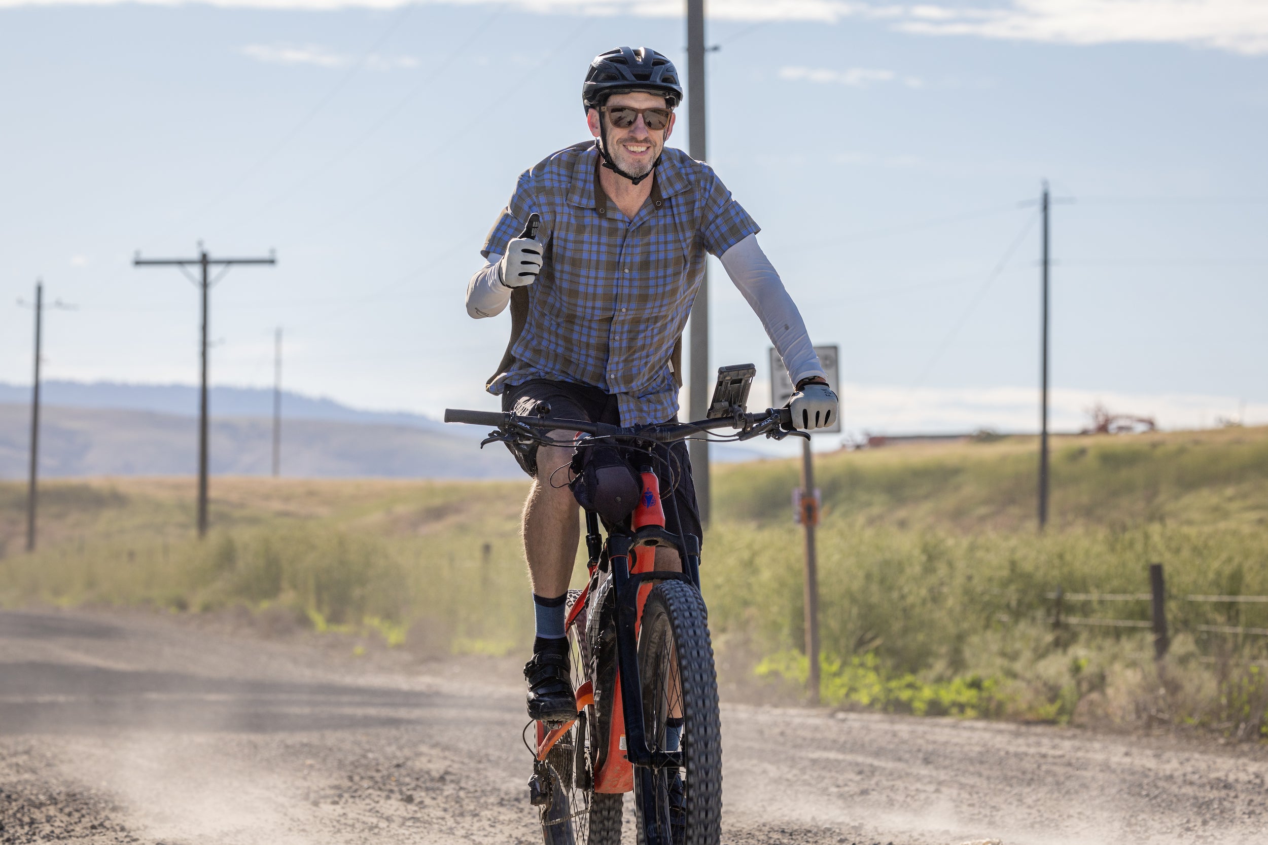 Clinical Associate Professor Travis Armstrong rides his bike and gives a 'thumbs up' to the camera.
