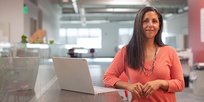 Woman standing at a table with laptop