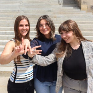 three members pose in front of capital steps