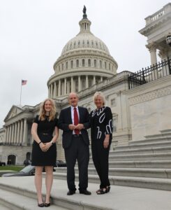 Three people stand in front of the capital