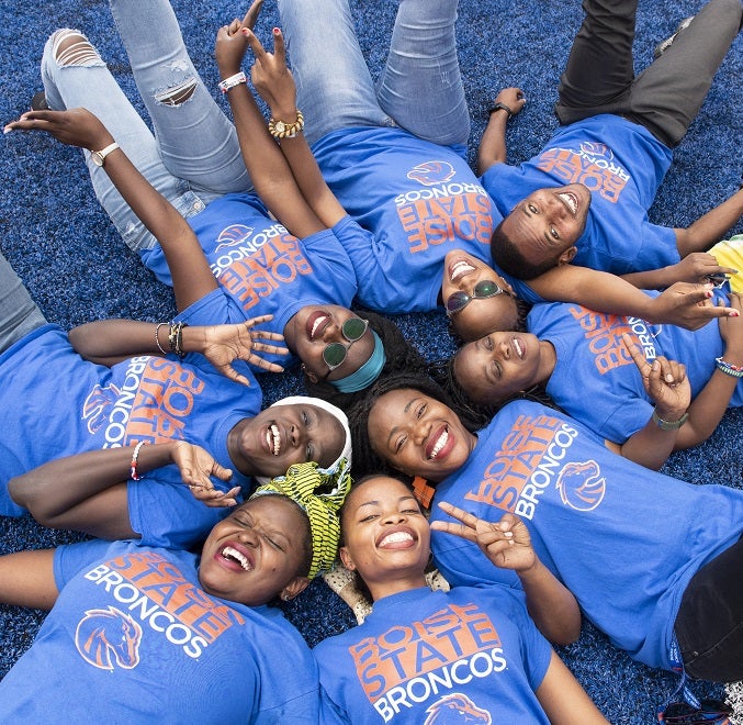 Group of 8 Africans lying down in a circle on Boise State's Blue Field