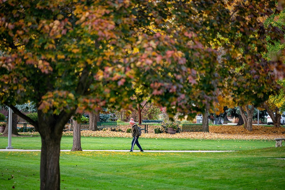 A student walking through campus in fall.
