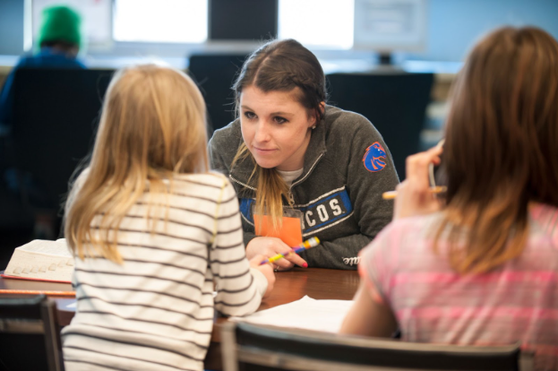 Boise State student working working at a desk one-on-one with a young elementary school student. 