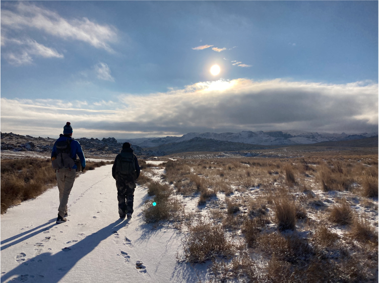 Two people walking in the wilderness on a snow-filled path