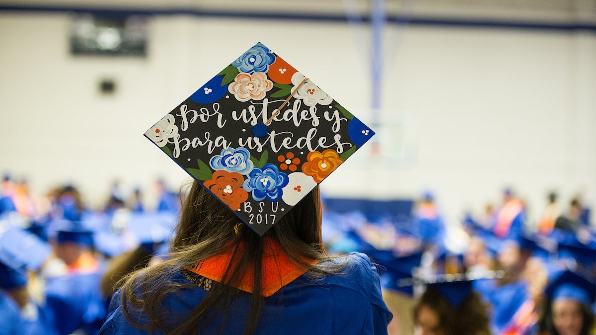 Student at commencement wearing cap that reads por ustedes y para ustedes